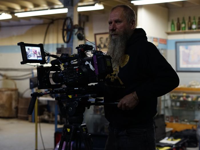 Frank Schlichting behind a cinema camera in a workshop full of old mining gear