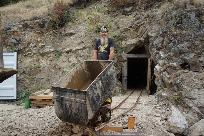 Frank behind an ore car on the rails outside the timbered portal of the Yankee Boy mine