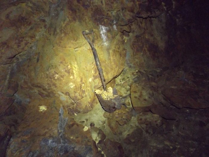 An old shovel leaning on a mineral-crusted rock wall in the Hidden Creek mine at Anyox, BC