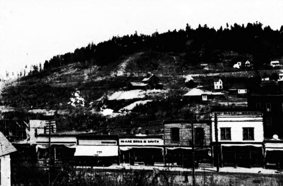 Phoenix, BC, in 1909: a row of shopfronts, one signed McRae Bros and Smith, below the Stemwinder mine on the hill