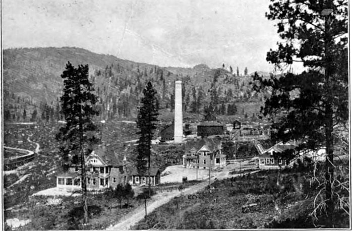 A halftone photograph of 1900: Granby&rsquo;s new smelter at Grand Forks, a tall stack and long sheds among pines on a hillside, with the company&rsquo;s offices in front