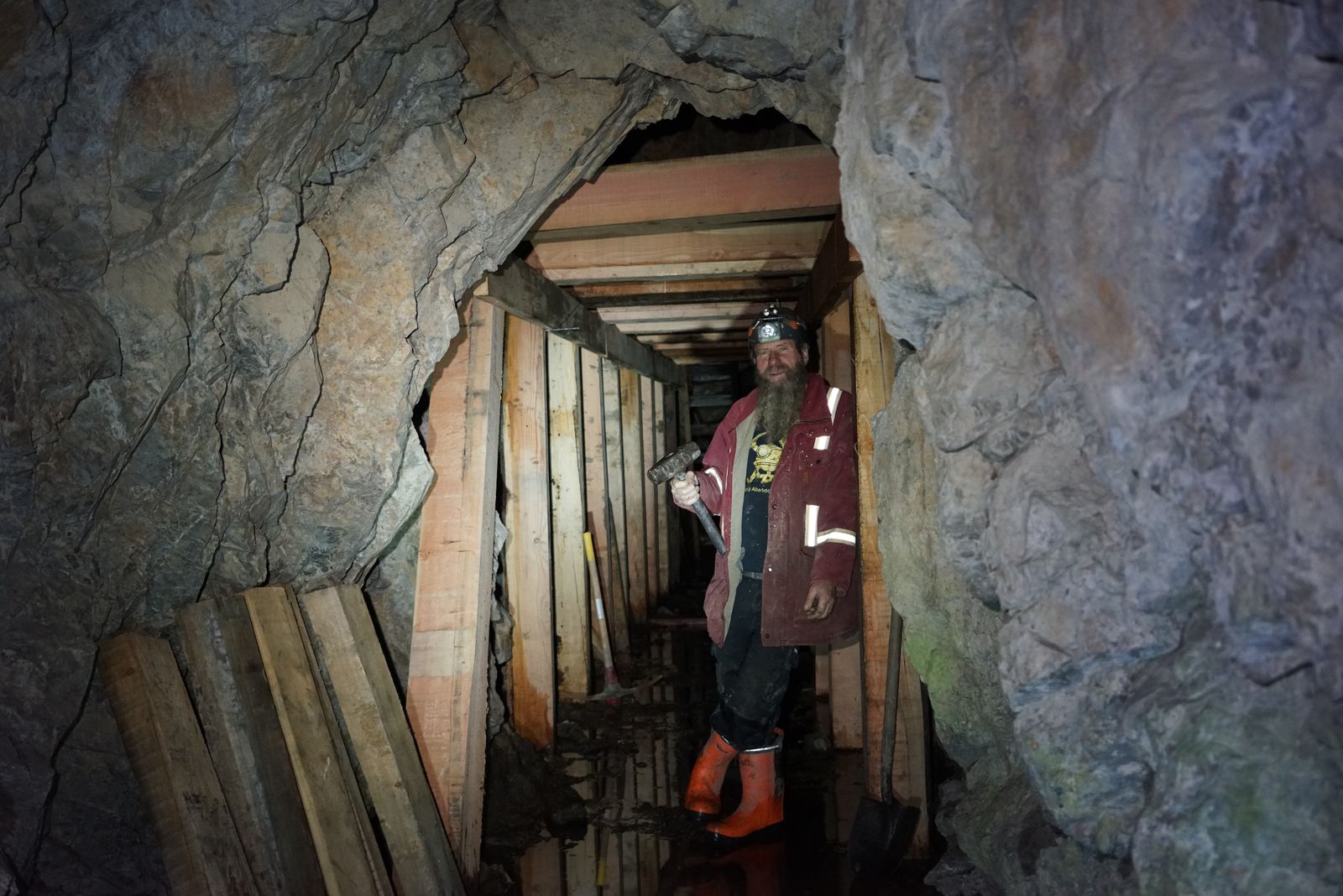 Frank Schlichting, sledgehammer in hand, standing in a tunnel of new timber sets inside the Yankee Boy mine